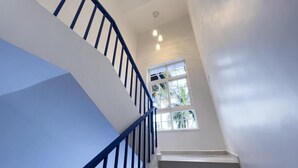 Un escalier avec des rampes bleues menant à un palier doté d’une fenêtre donnant sur un espace verdoyant.