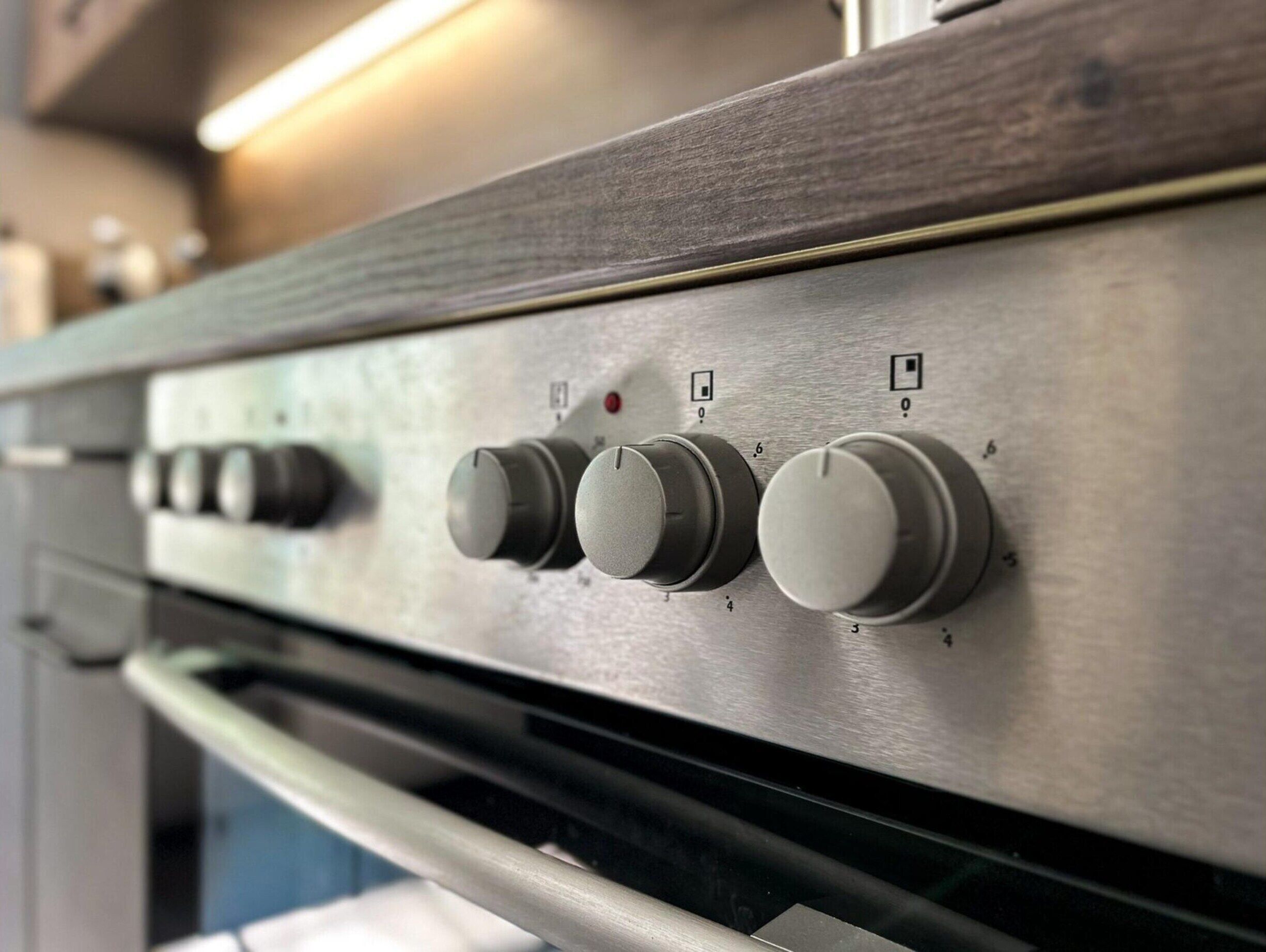 A kitchen with stainless steel appliances, including a stove with four knobs and a microwave.