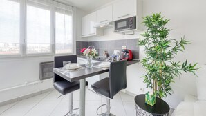 Una cocina moderna con armarios blancos, un microondas y un comedor con una mesa lista para dos.