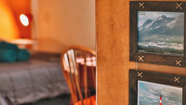 A wooden wall with two framed pictures of Ushuaia landscapes.