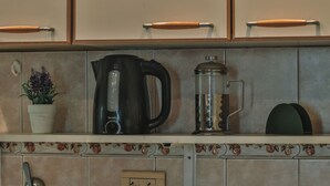 A kitchen with a coffee maker, a kettle, and a French press.