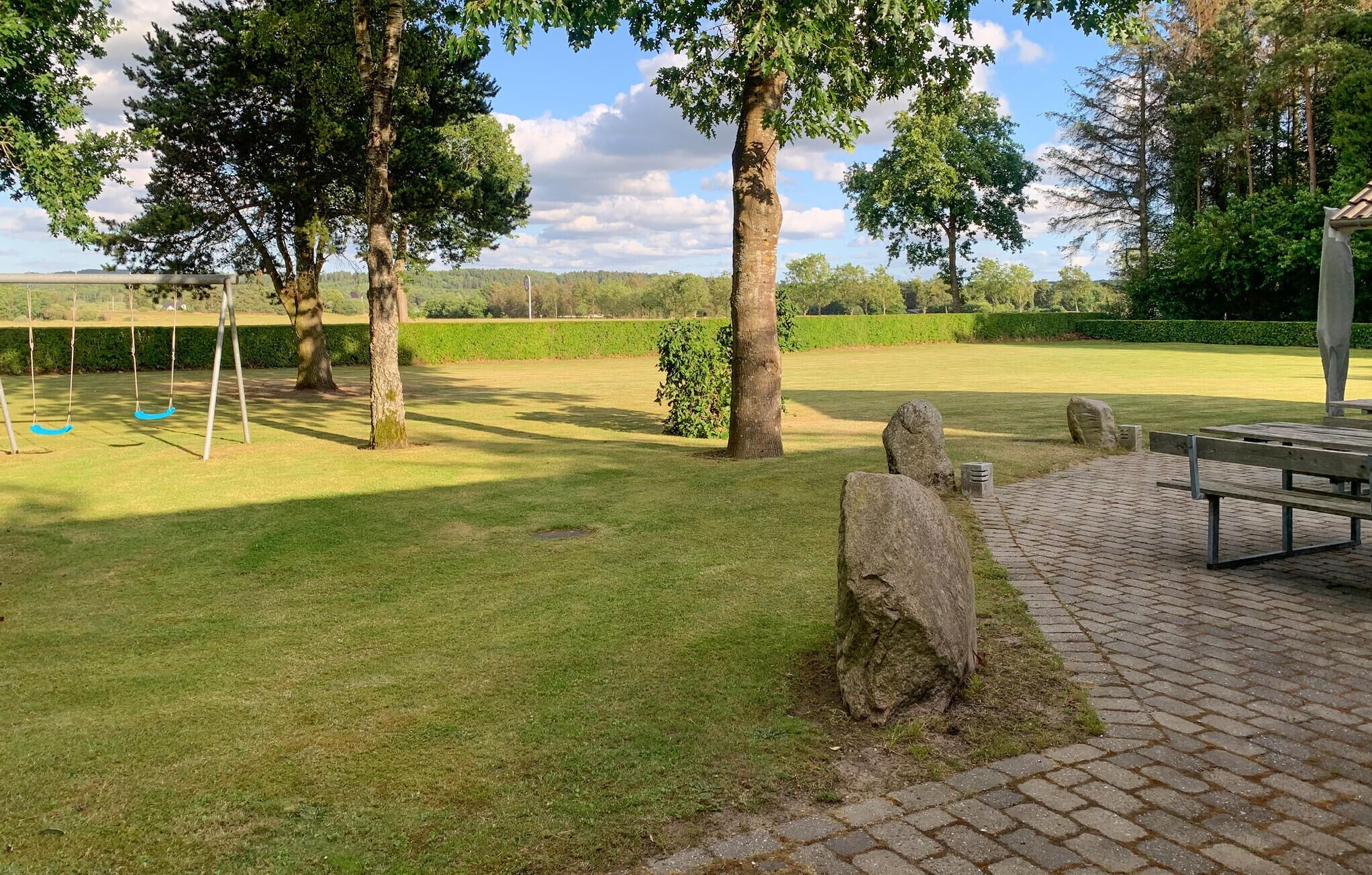 A park with a picnic table, swings, and a stone path.