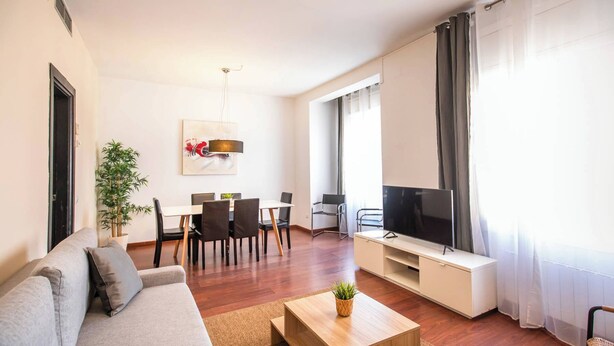 Un salon moderne comprenant un canapé, une table basse, un coin repas et un téléviseur.