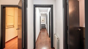Un couloir étroit, doté d’un plancher en bois et de portes encadrées de noir de part et d’autre.