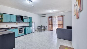 Eine moderne Küche mit türkisfarbenen Schränken, ein Essbereich mit einem runden Tisch und ein graues Sofa.