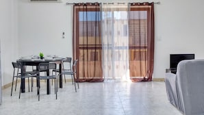 Ein Zimmer mit Esstisch für vier Personen, einem Fernseher und einer Couch.