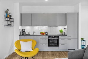 A modern kitchen with grey cabinets, a built-in oven, and a coffee machine. - Modern apartment with terrace, partial sea view and private parking in Travemünd (Lübeck)
