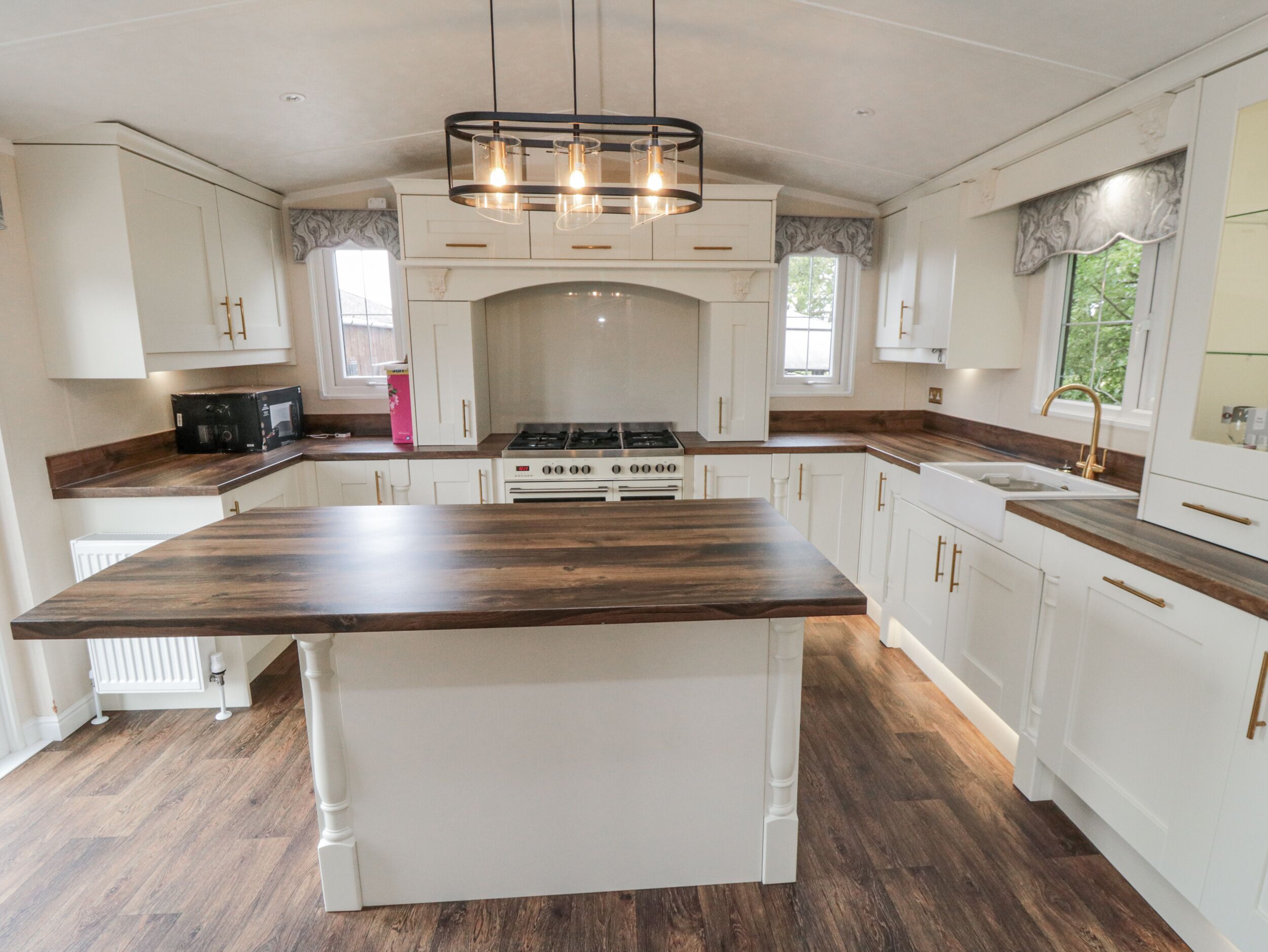 A kitchen with white cabinetry, a central island, a gas stove, and a pendant light fixture.