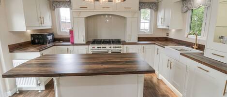A kitchen with white cabinetry, a central island, a gas stove, and a pendant light fixture.