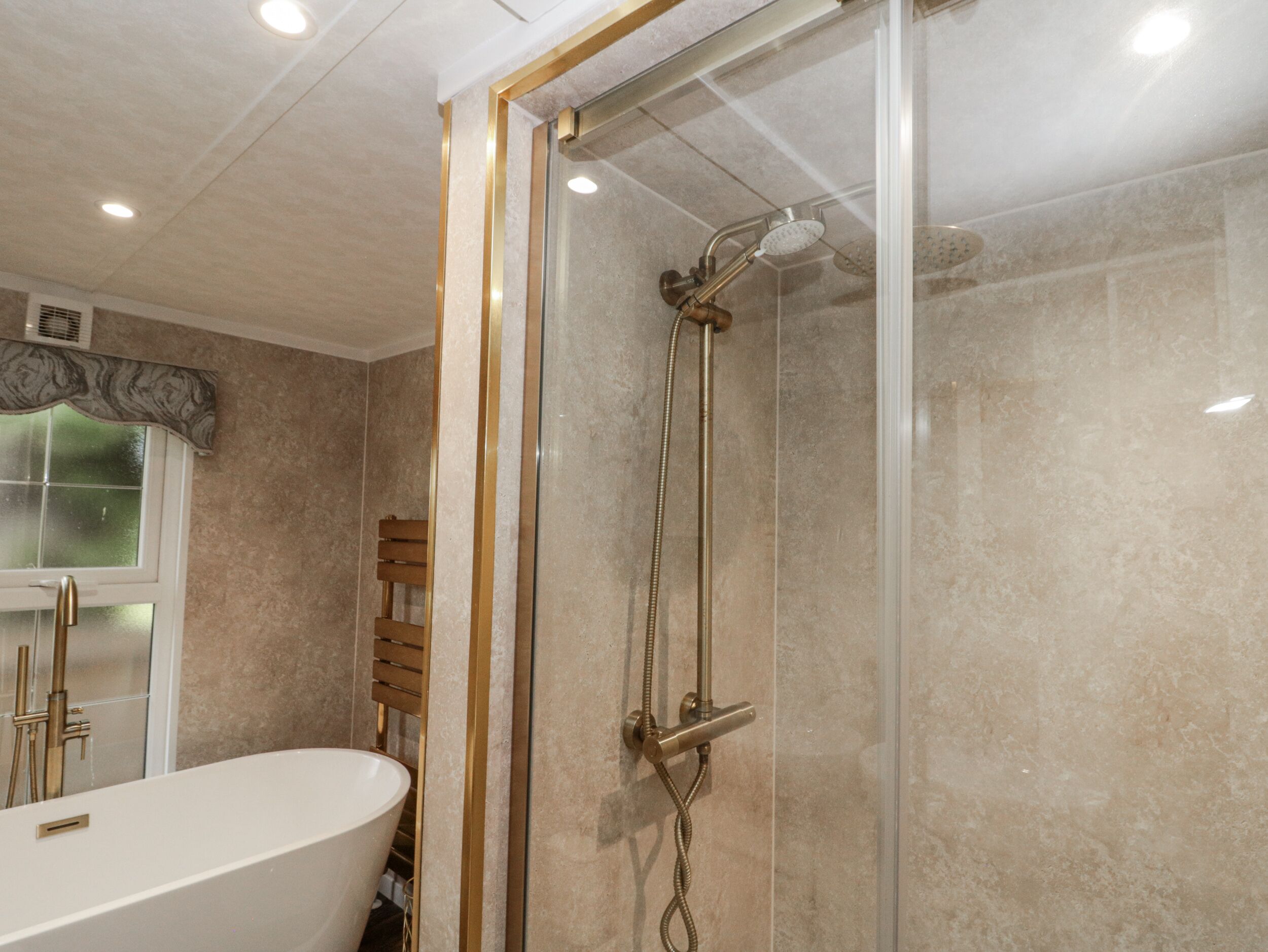 A bathroom with a glass-enclosed shower, a freestanding bathtub, and a window with frosted glass.