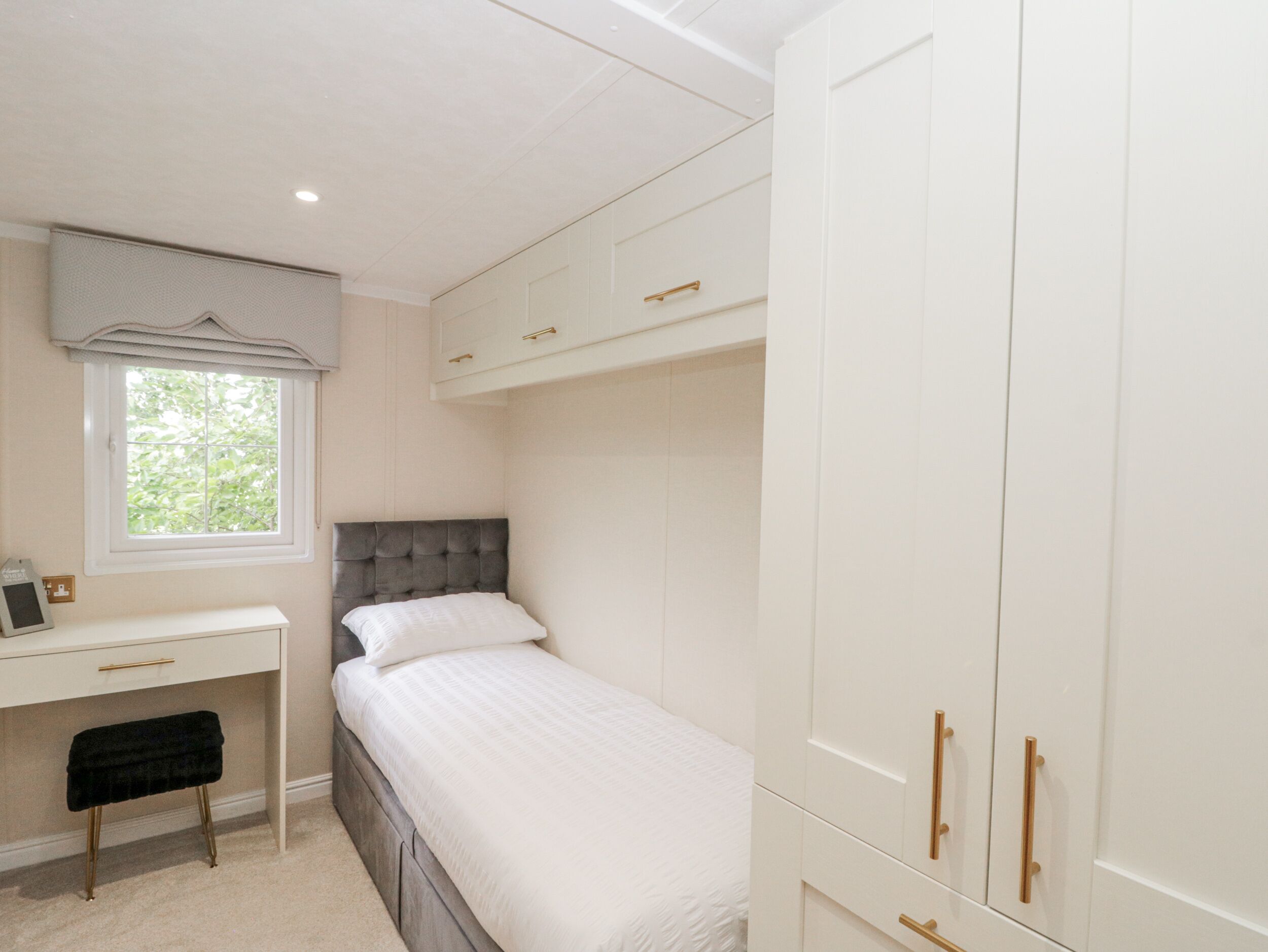 A bedroom with a bed, a desk, and a wardrobe.