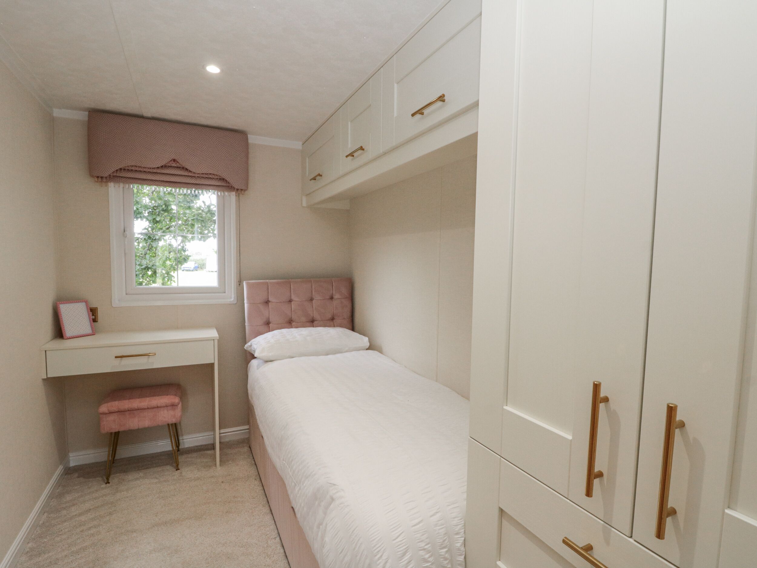 A bedroom with a single bed, a desk, and a wardrobe.