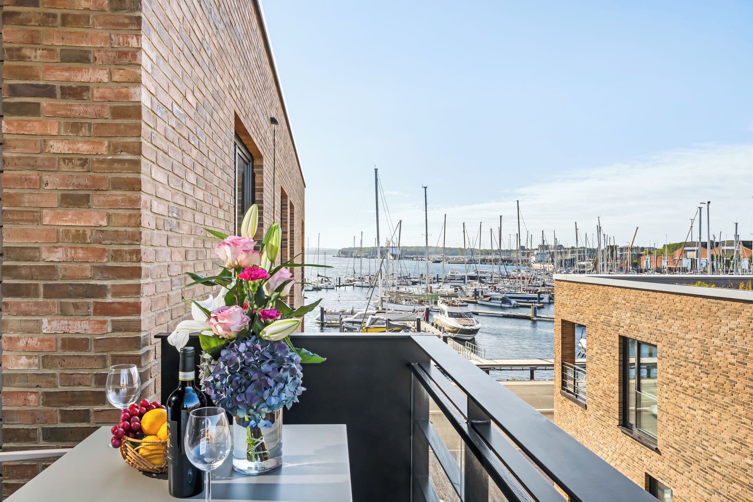 Ein Balkon mit Esstisch mit Blick auf eine Marina und Boote.