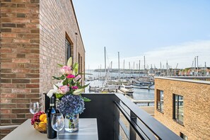 A balcony with a table set for dining, overlooking a marina with boats. - Modern apartment with terrace, private parking and sea view in Travemünde (Lübeck)