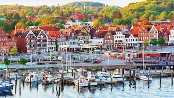 Ein Yachthafen mit angestaubten Booten, umgeben von traditionellen Gebäuden im europäischen Stil mit roten Dächern und weißen Fassaden.