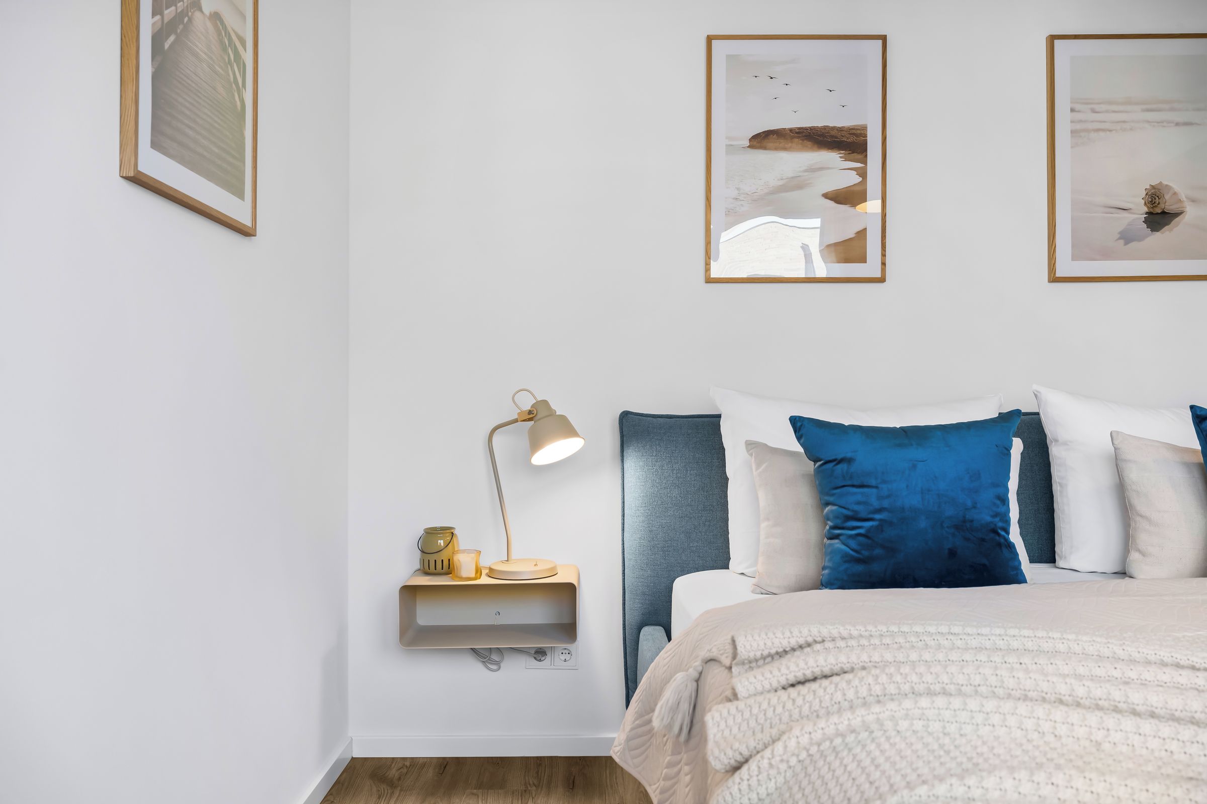 Ein Schlafzimmer mit Bett, Nachttisch, Lampe und Wandbild.
