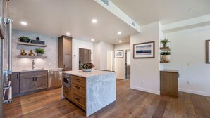 A spacious kitchen with wooden cabinets, a marble island, and built-in shelving. - Slope! There It Is! | Includes Two 1-Day Lift Tickets (Tamarack)