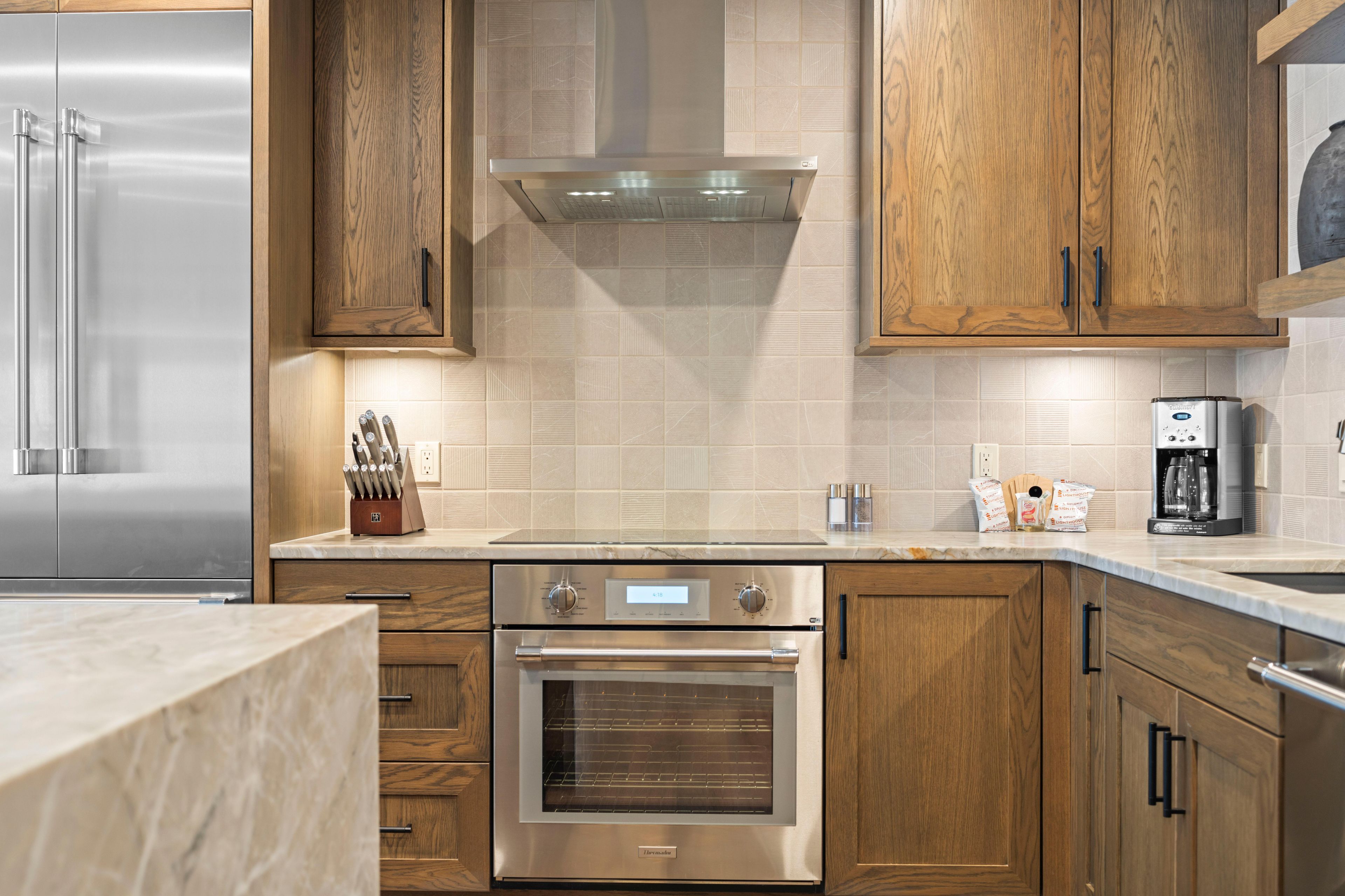 A modern kitchen with stainless steel appliances, wooden cabinets, and a tiled backsplash.