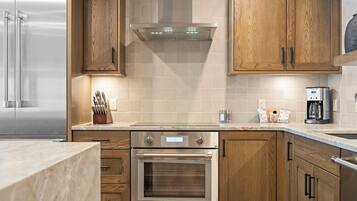 A modern kitchen with stainless steel appliances, wooden cabinets, and a tiled backsplash.