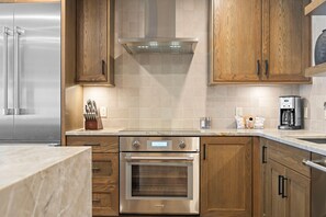 A modern kitchen with stainless steel appliances, wooden cabinets, and a tiled backsplash. - Slope! There It Is! | Exclusive Tamarack Perks (Tamarack)