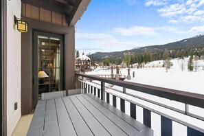 Una terraza de madera con vistas a un paisaje nevado de montañas.