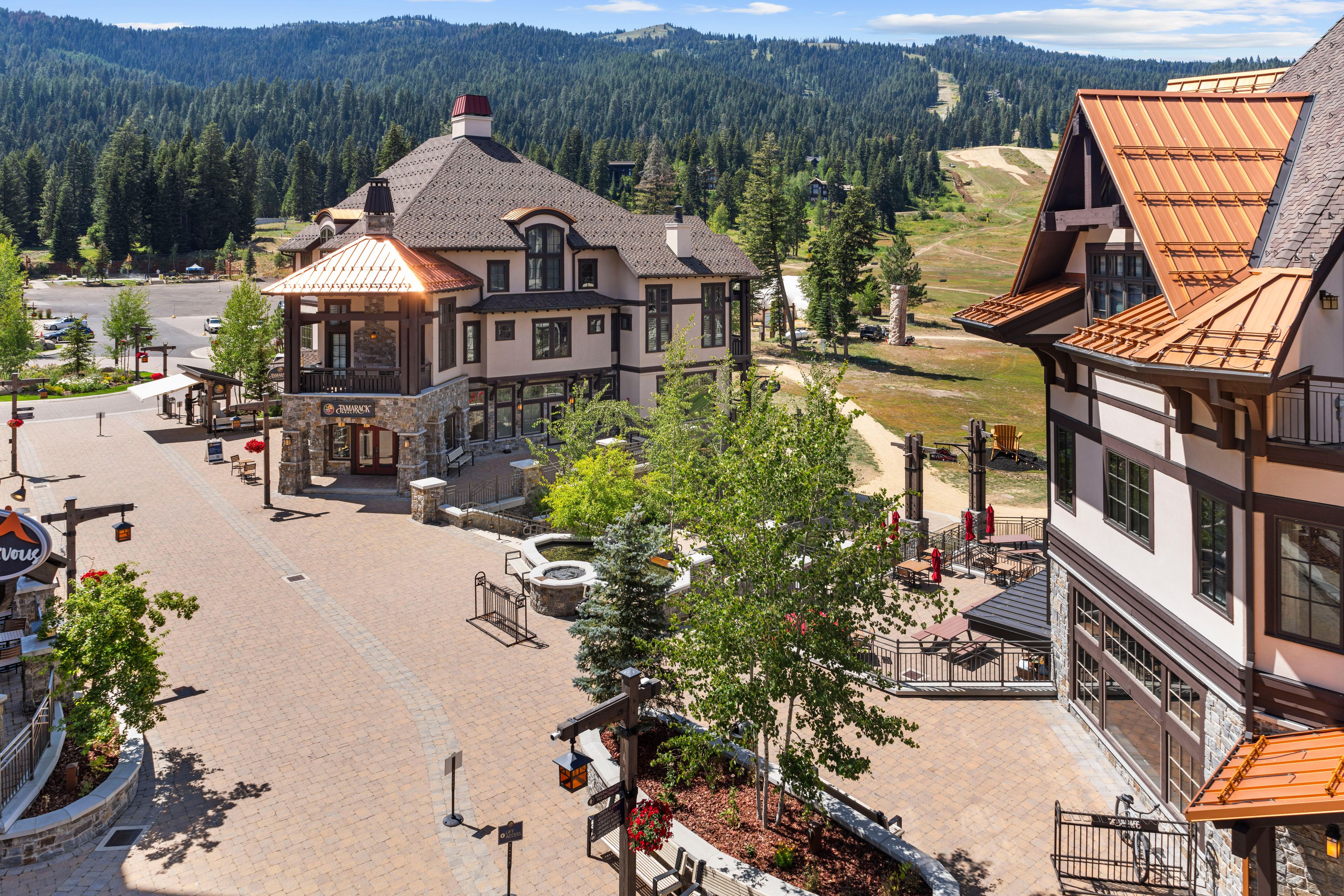 Ein Hotel mit einer Steinglasfassade, zahlreichen Fenstern und einem gepflasterten Innenhof mit Außenbestuhlung.