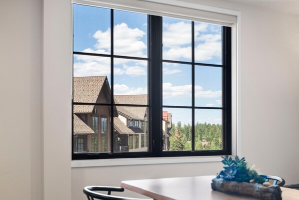 A room with a large window, a table, and a chair.