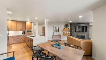 Une cuisine moderne avec des meubles en bois, un îlot central et un coin repas comprenant une table et des chaises en bois.