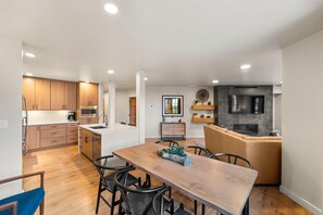 Una cocina moderna con armarios de madera, una isla central y un comedor con mesa y sillas de madera.