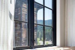 A window with a view of a building and a mountain.