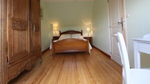 Une chambre à coucher avec un lit en bois, deux lampes de chevet, une armoire et une porte.