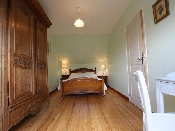 Une chambre à coucher avec un lit en bois, deux lampes de chevet, une armoire et une porte.