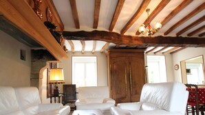 Un salon avec des canapés en cuir blanc, une table basse en bois et un grand meuble en bois.
