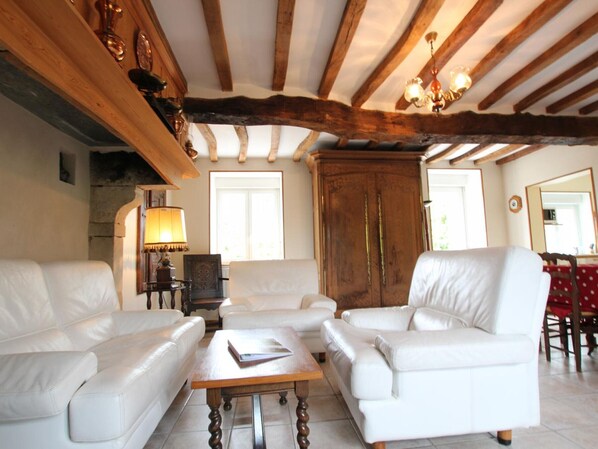 A living room with white leather sofas, a wooden coffee table, and a large wooden cabinet.