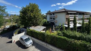 Ein mehrstöckiges Wohngebäude mit Balkonen, einem Parkplatz und umliegender Bepflanzung.