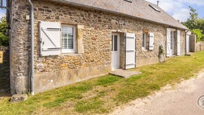 Une ferme en pierre avec un chemin de terre menant à l’entrée.