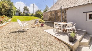 Un espace extérieur aménagé en patio, avec un sol en gravier, des sièges et un bâtiment en pierre.
