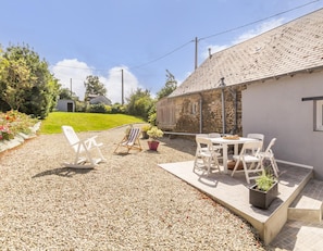 A patio area with a gravel surface, outdoor seating, and a stone building.