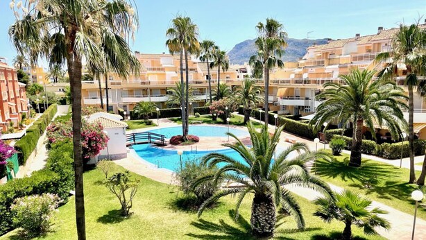A resort with a central swimming pool, palm trees, and a mountainous backdrop. - Bright duplex with pool and parking in Denia (Denia)