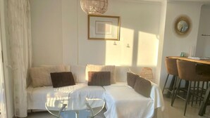 A modern living room with a sofa, a glass coffee table, and a dining area with chairs. - Bright duplex with pool and parking in Denia (Denia)