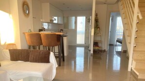A modern living room with a glass coffee table, a sofa, and a kitchen in the background. - Bright duplex with pool and parking in Denia (Denia)