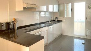 A modern kitchen with white cabinets, a black countertop, and a built-in dishwasher. - Bright duplex with pool and parking in Denia (Denia)