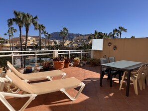 A terrace with lounge chairs, a table, and potted plants. - Bright duplex with pool and parking in Denia (Denia)