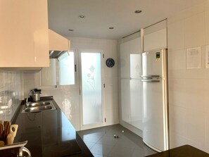 A modern kitchen with white cabinets, a stainless steel sink, and a refrigerator. - Bright duplex with pool and parking in Denia (Denia)