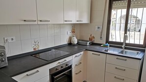 Eine moderne Küche mit weißen Schränken, einer schwarzen Arbeitsplatte und einem Backofen. Ein Fenster bietet Blick ins Freie.