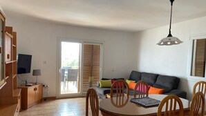 Ein modernes Wohnzimmer mit Essbereich, einer Couch und einem Fernseher.