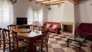 Una sala de estar con una mesa de comedor de madera, un sofá rojo, una chimenea y un televisor.