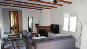Una sala de estar con sofá, sillones, chimenea, televisor y un ventanal grande.