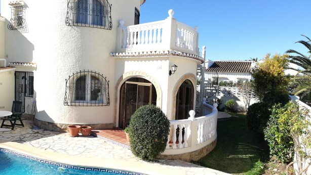 Una villa blanca con piscina, terraza cubierta y jardín.