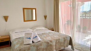 A hotel room with a bed, two pillows, a nightstand, a lamp, a mirror, and a window with curtains. - Penthouse in Denia with air conditioning and private parking (Denia)